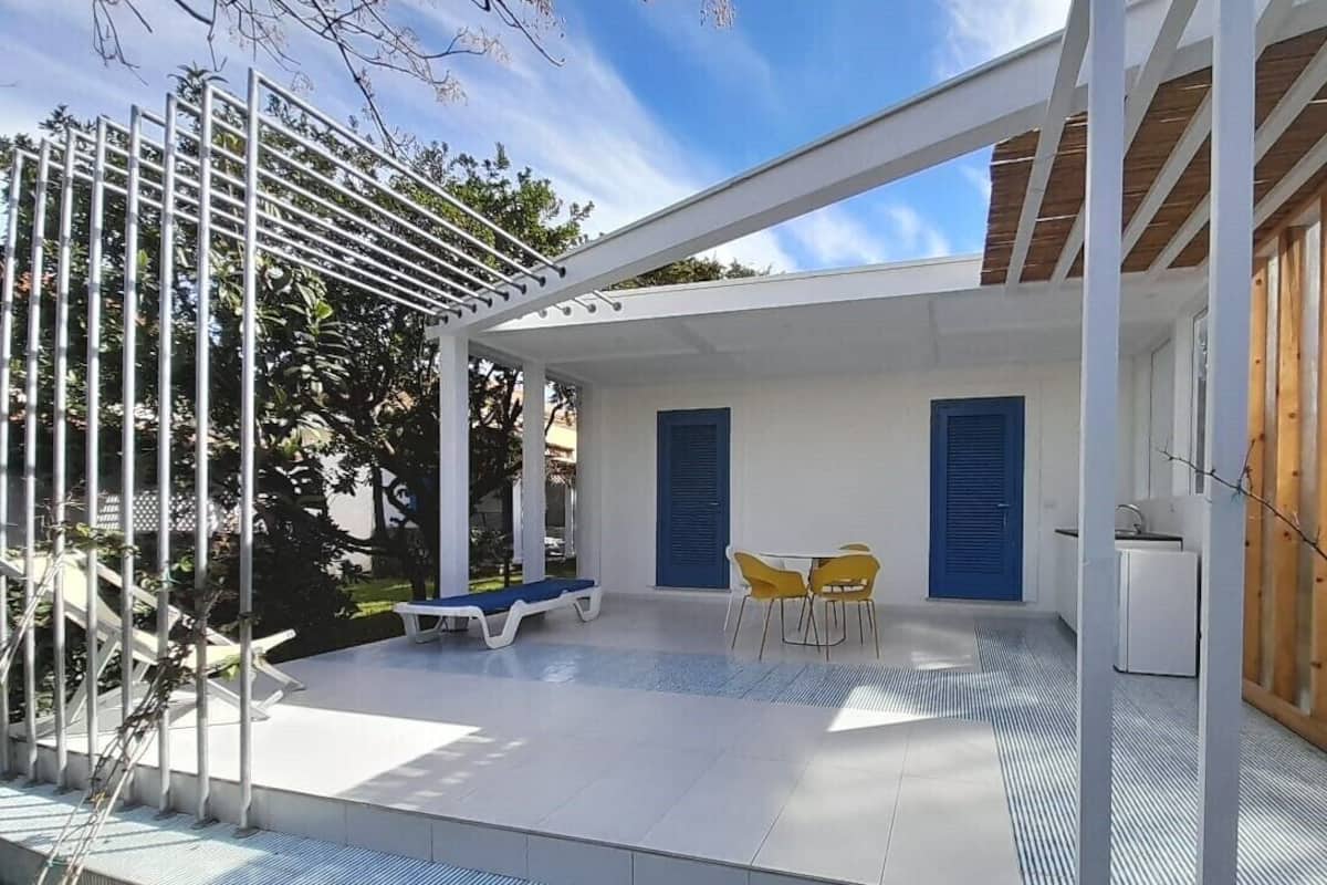 Une terrasse extérieure moderne avec une balustrade blanche, une porte bleue et un petit coin cuisine.