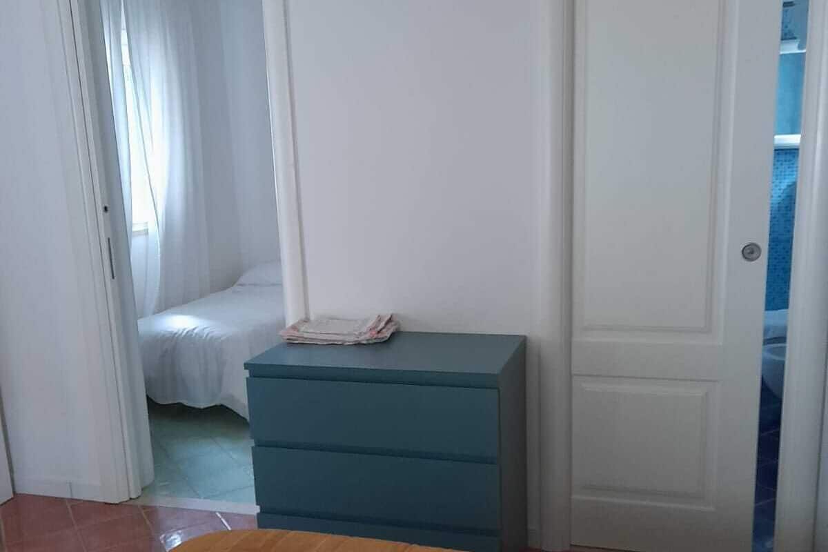 Une chambre à coucher comprenant un lit, une commode et une porte donnant sur une autre pièce.