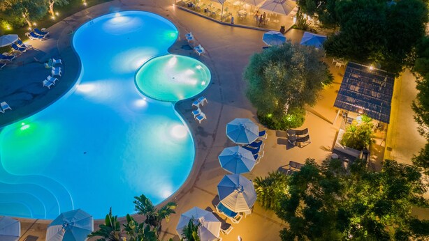 Vue aérienne d’un complexe hôtelier doté de plusieurs piscines, de chaises longues et de parasols.