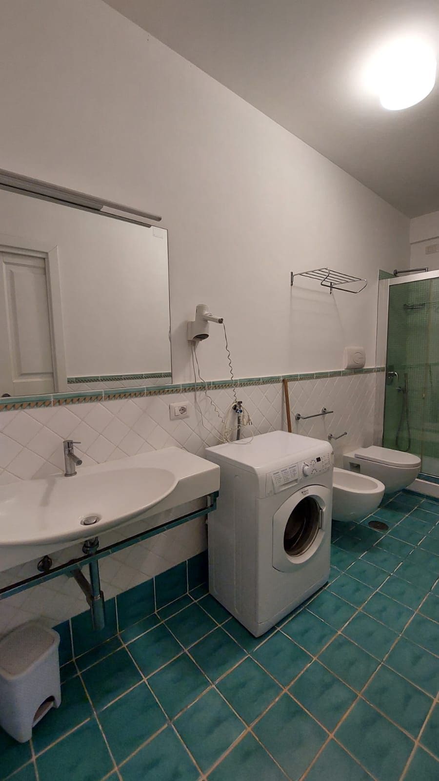 Ein Badezimmer mit Waschmaschine, zwei Waschbecken, Toilette und Dusche.