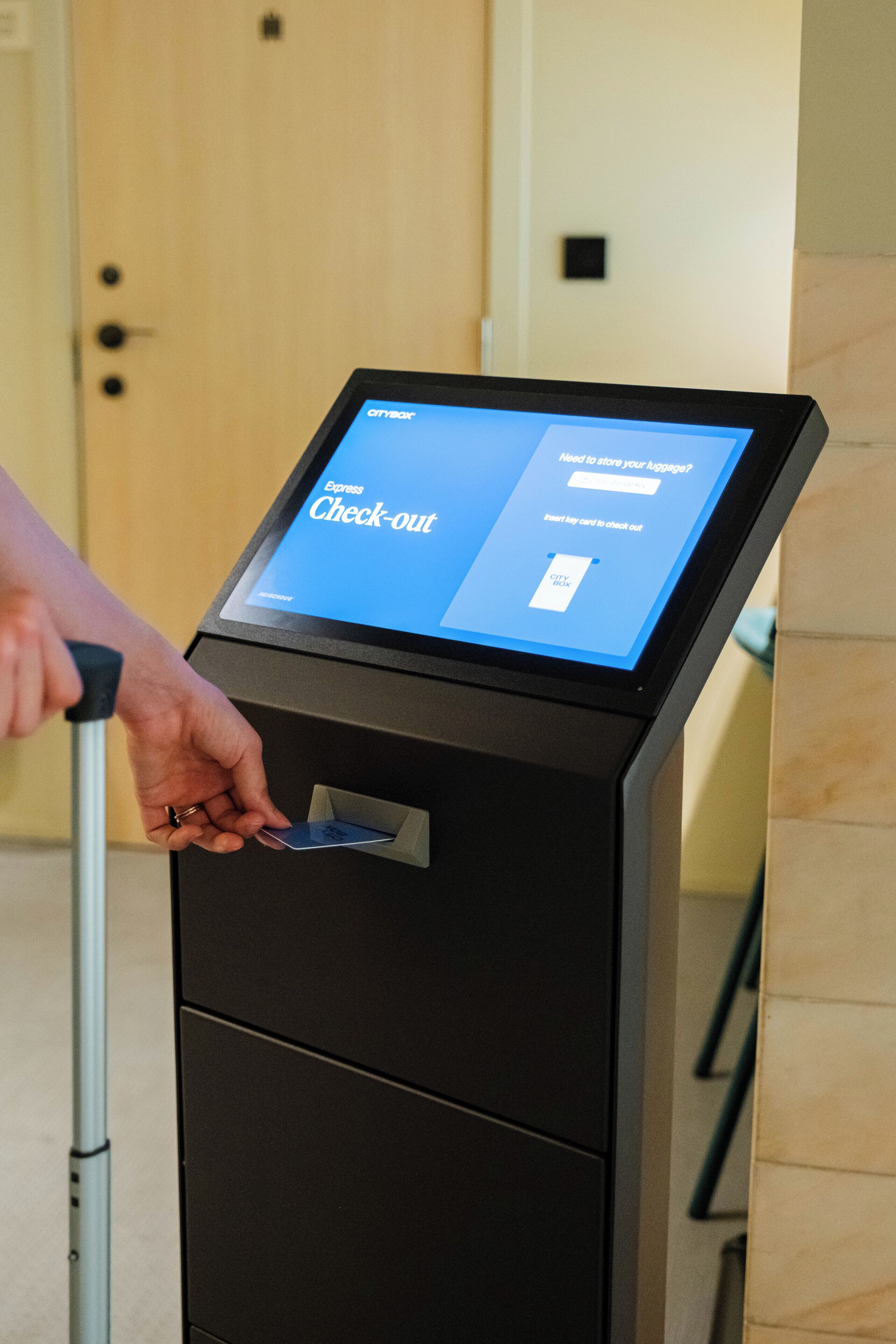 A person using a check-out kiosk with a digital screen displaying the 'Express Check-out' interface.