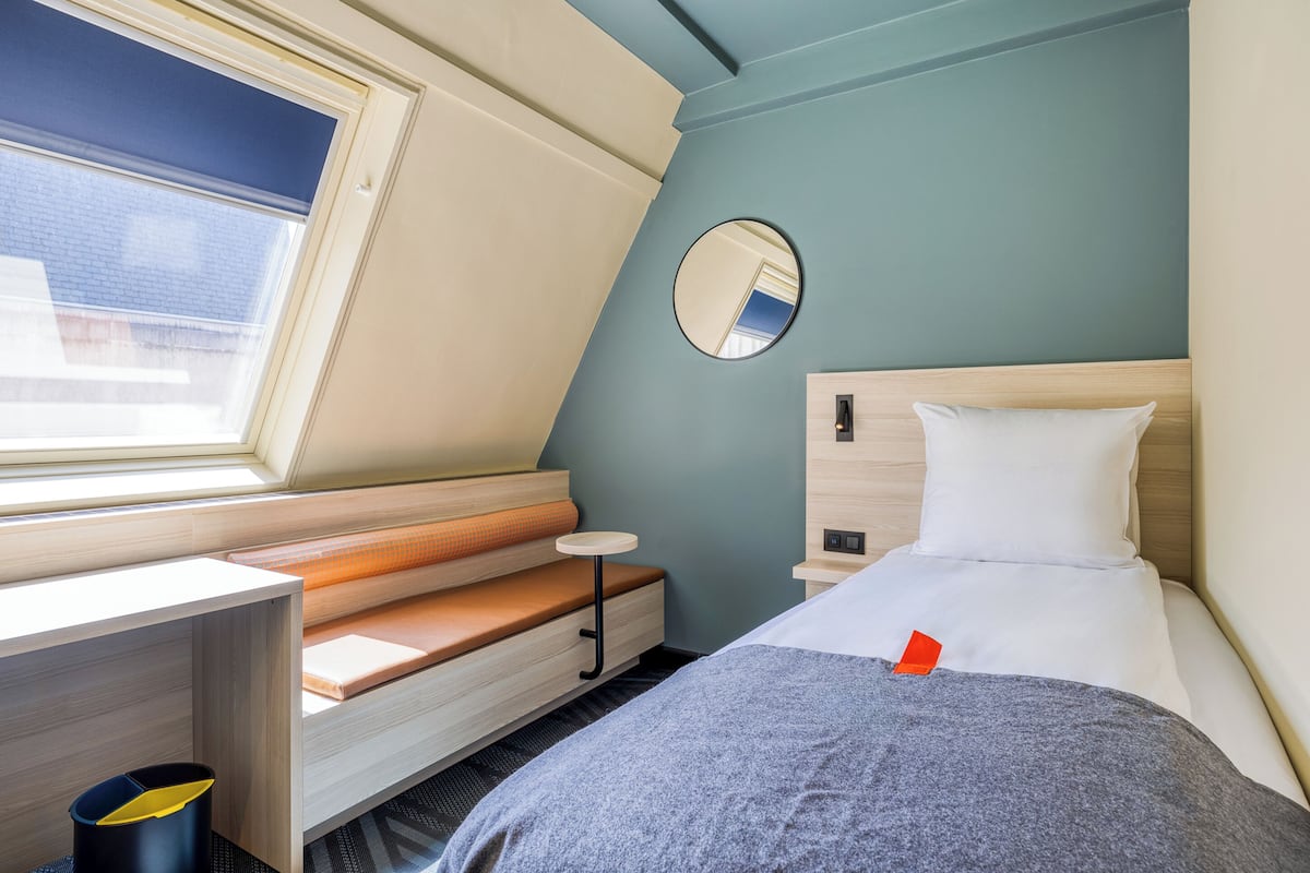 A modern, compact room with a bed, a small table, and a bench.