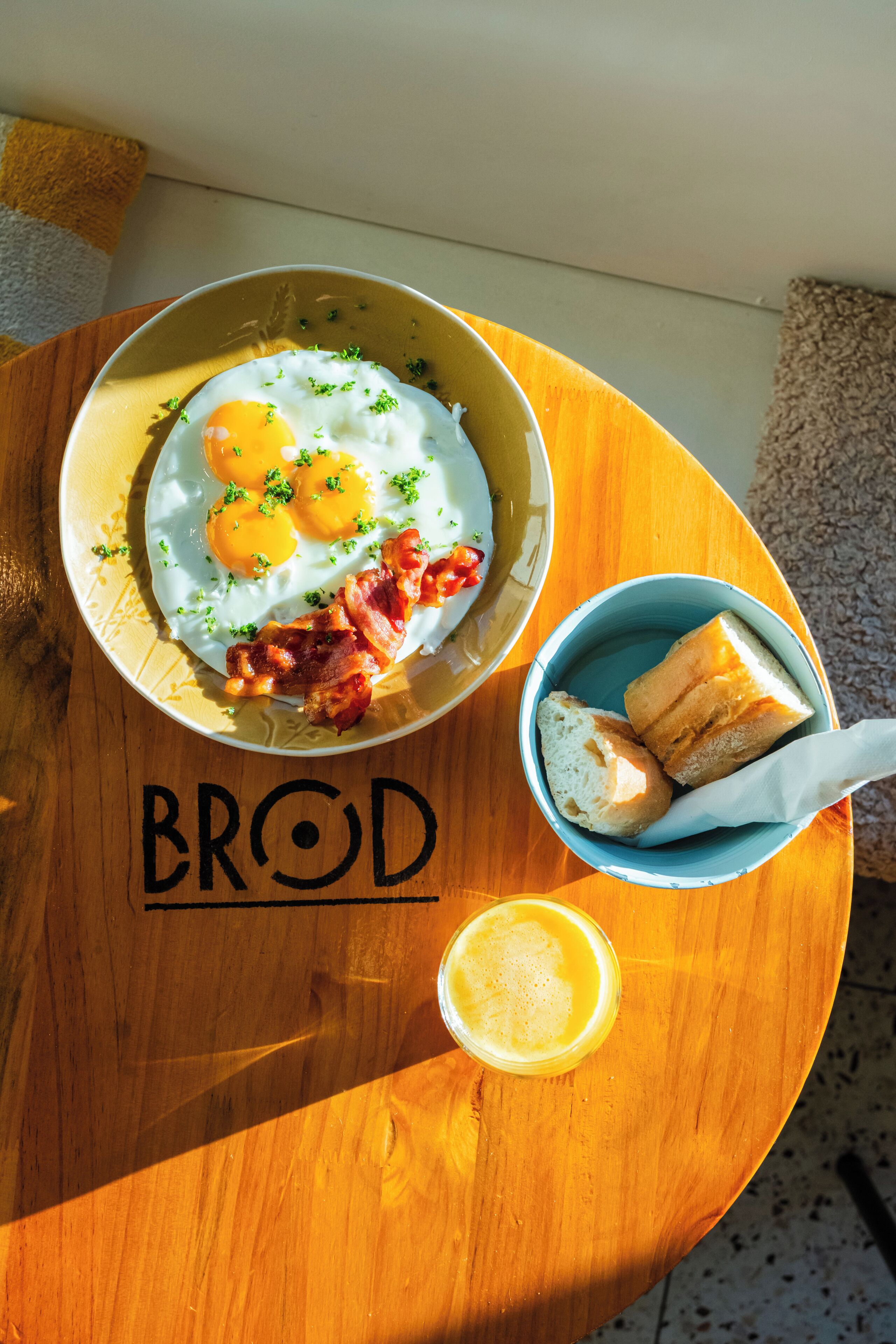 Un plato de desayuno con huevos, tocino y tostadas sobre una mesa de madera.