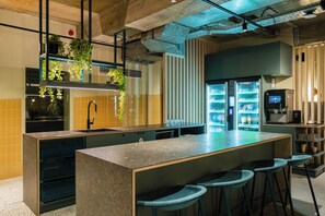 A modern kitchen with a central island, bar stools, a built-in refrigerator, and hanging plants. - Citybox Brussels Centre Louise (Brussels)