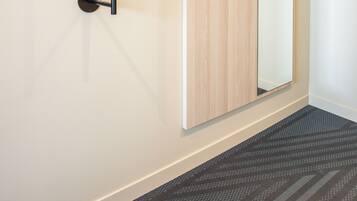 A modern room with a wooden door, a black vertical handle, and a mirror.