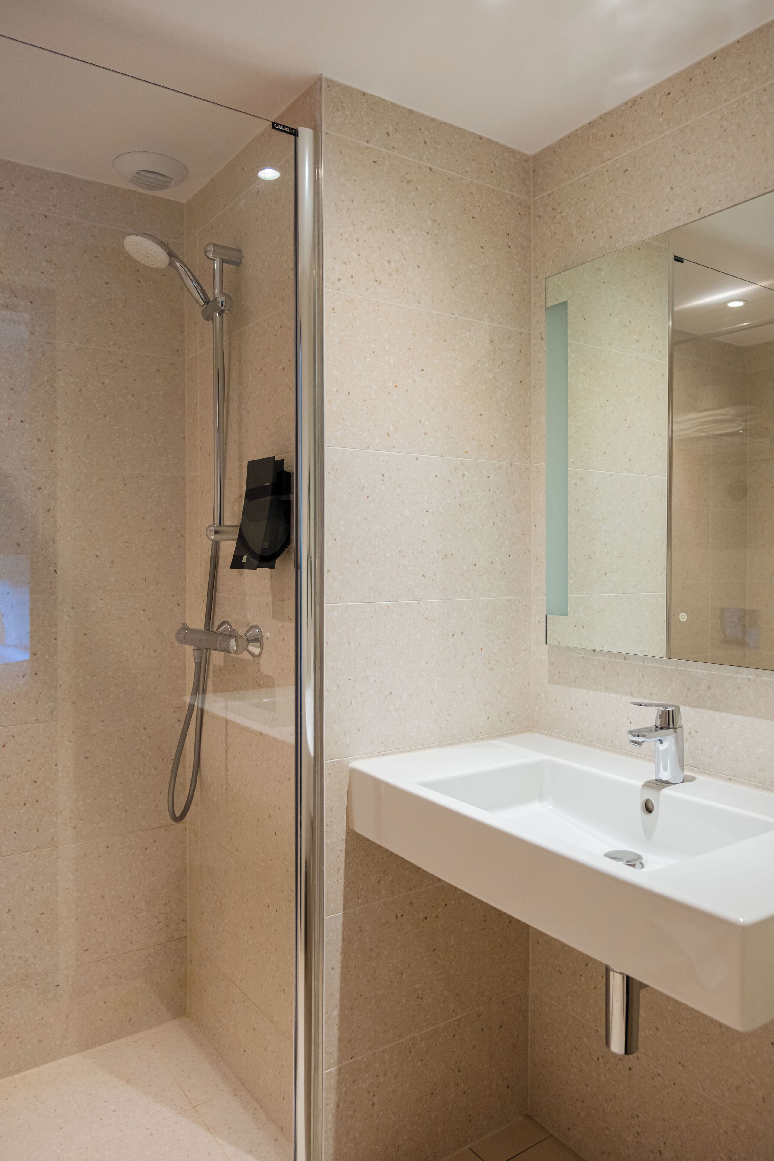 Een moderne badkamer met een douchecabine van glas, een wit wastafelmeubel en een grote spiegel.