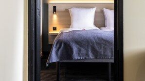A hotel room with a bed, a nightstand, and a wall-mounted lamp. - Citybox Brussels Centre Louise (Brussels)