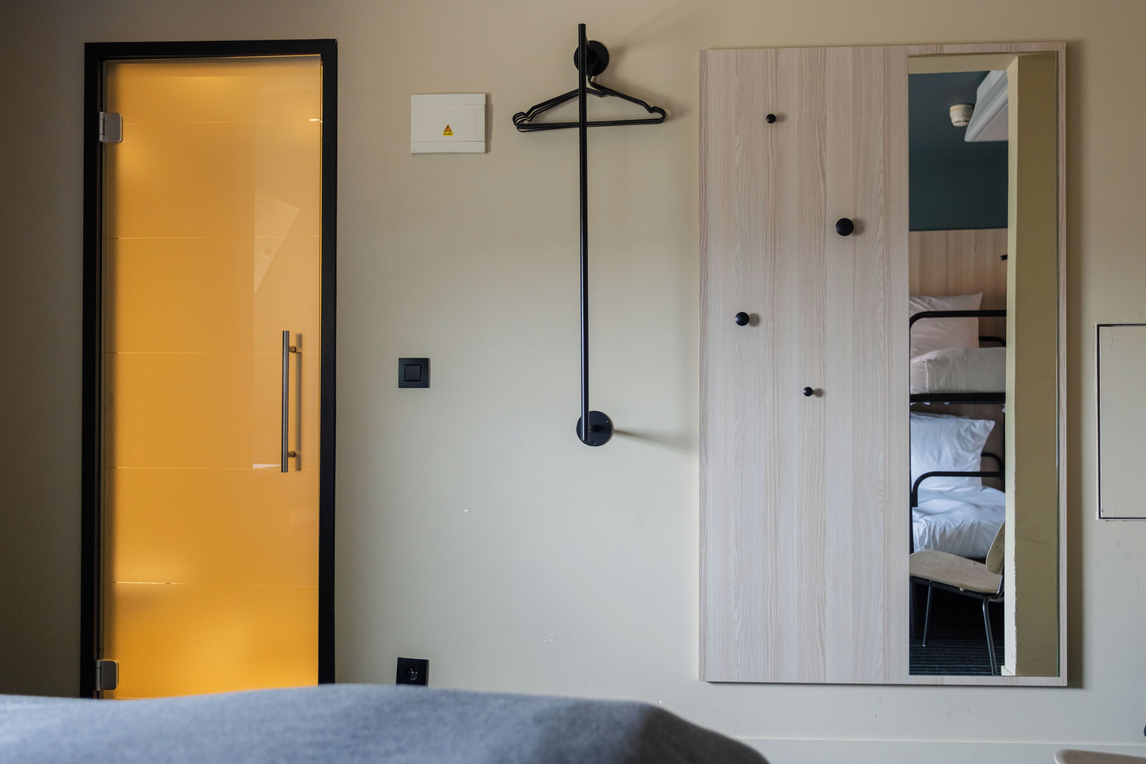 A hotel room with a bed, a wardrobe, a coat rack, and a mirror.