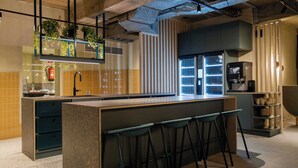 A modern kitchen with a central island, bar stools, a coffee machine, and vertical blinds. - Citybox Brussels Centre Louise (Brussels)