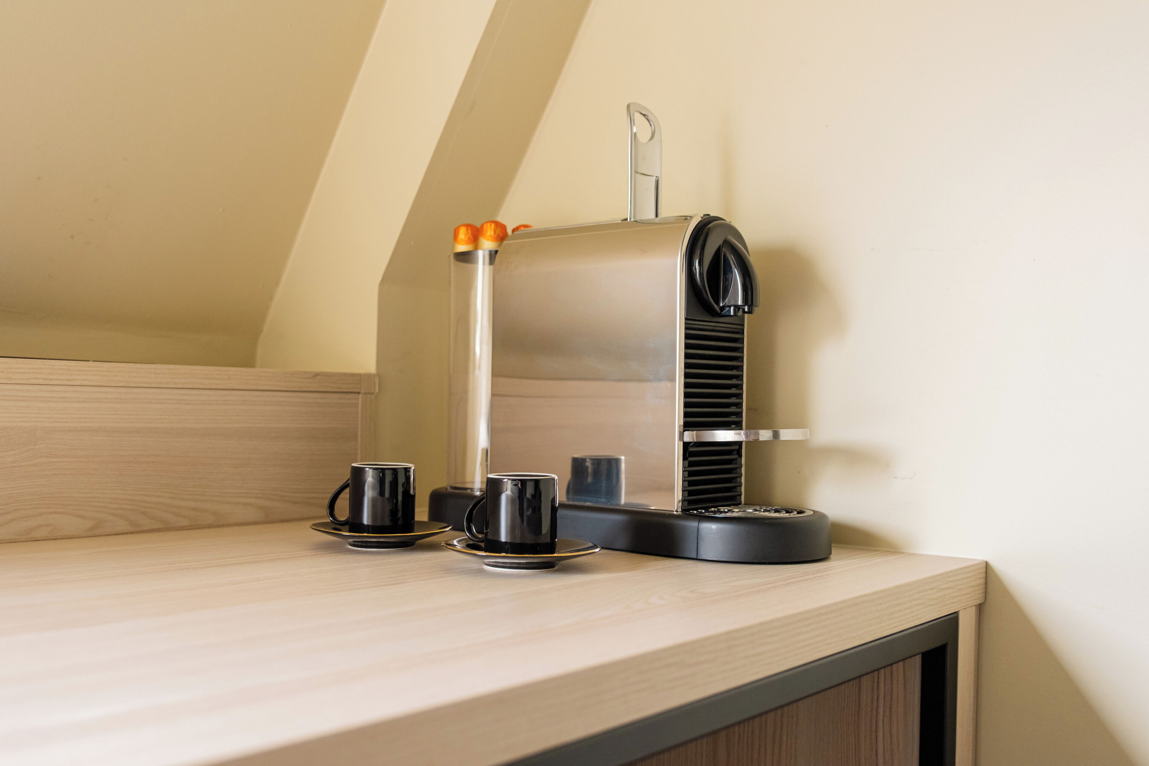 Une machine à café posée sur un comptoir en bois, avec deux tasses à côté.
