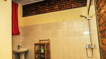 Un baño con lavamanos, ducha y repisa con artículos de aseo.