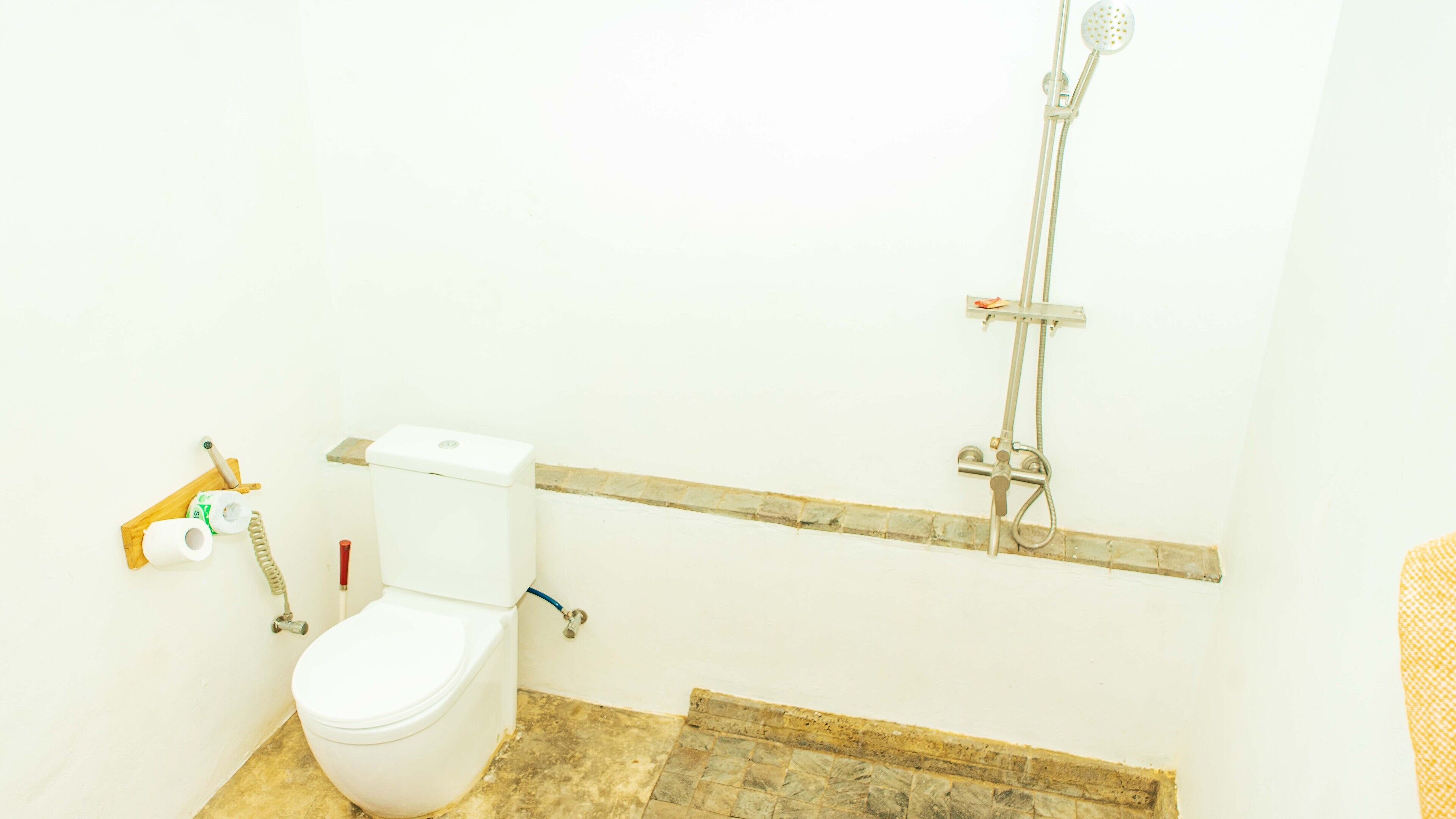 Un baño con inodoro, ducha y estante de madera.