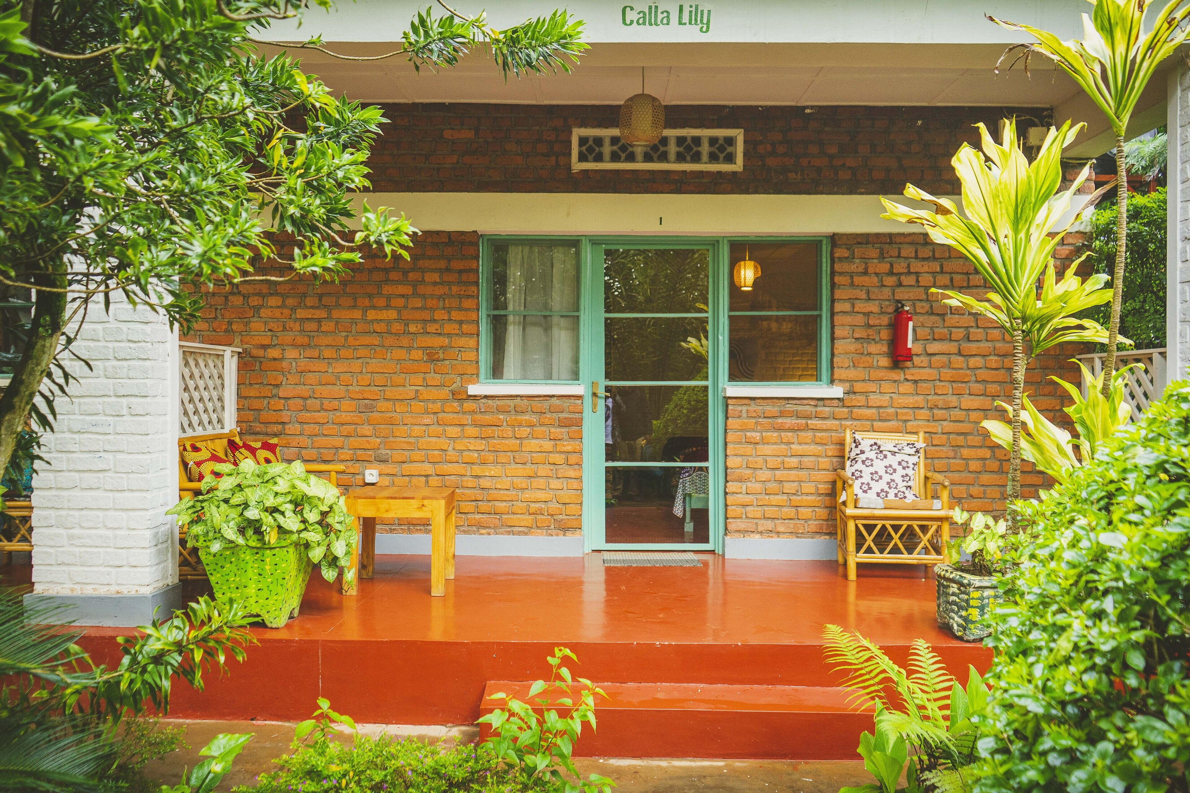Un edificio de ladrillo con una puerta verde, un banco y plantas en macetas en la fachada.