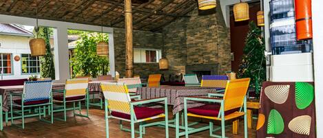 A restaurant with outdoor seating, wicker hanging lamps, and a Christmas tree.