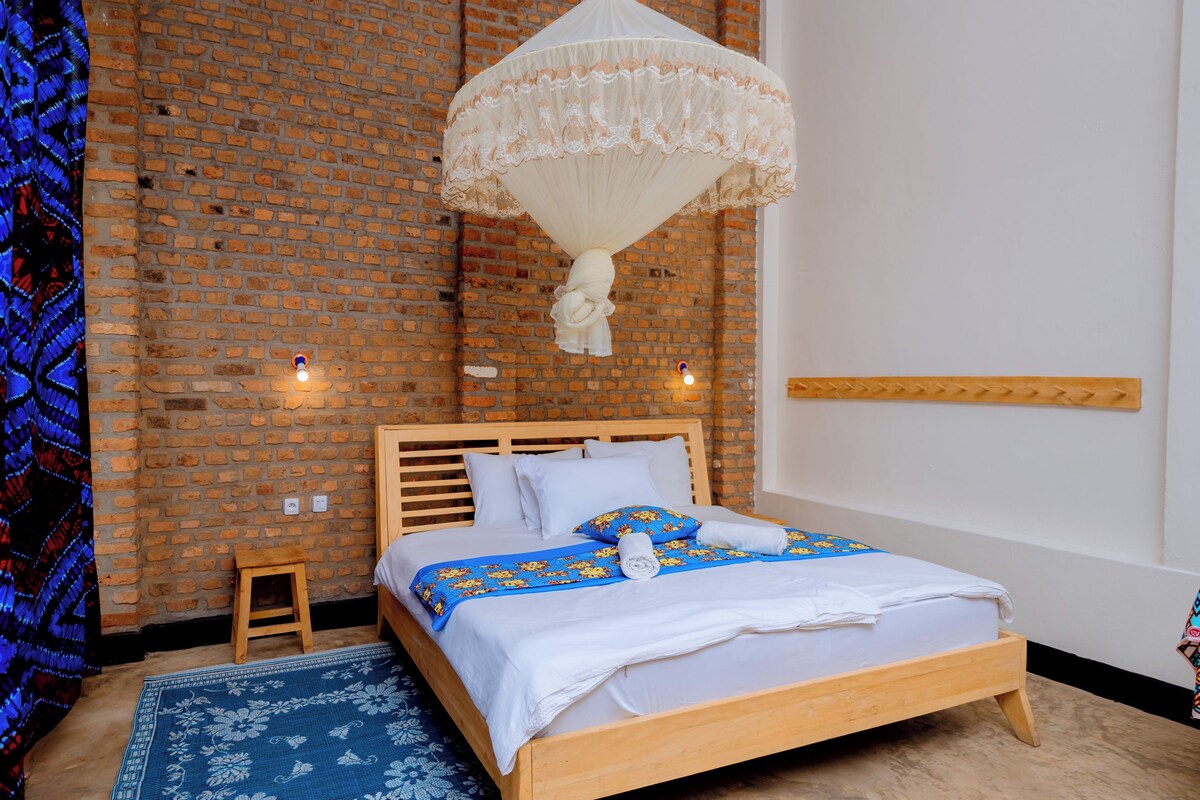 A neatly made bed with a wooden headboard, a blue floral bedspread, and a white canopy overhead.