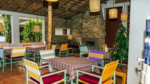 Un restaurante con terraza, paredes de piedra y lámparas de mimbre colgantes.
