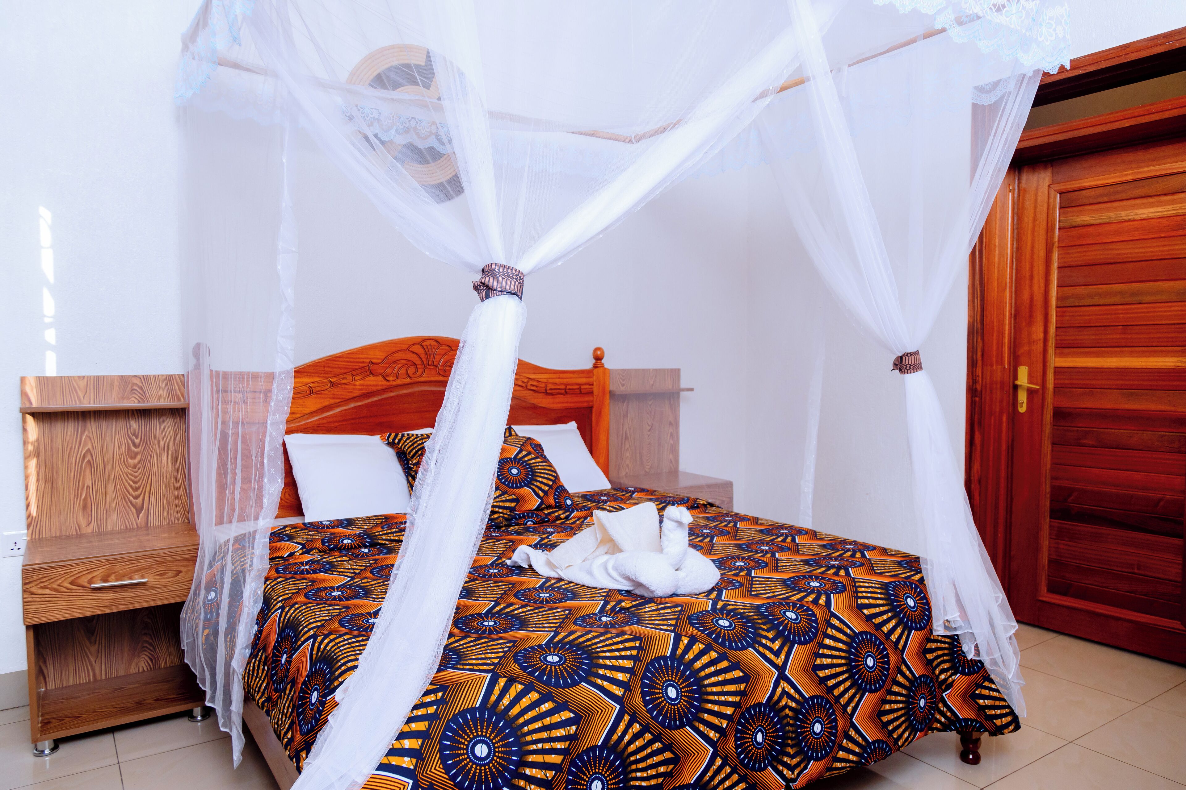 A bed with a canopy, a wooden nightstand, and a red door.