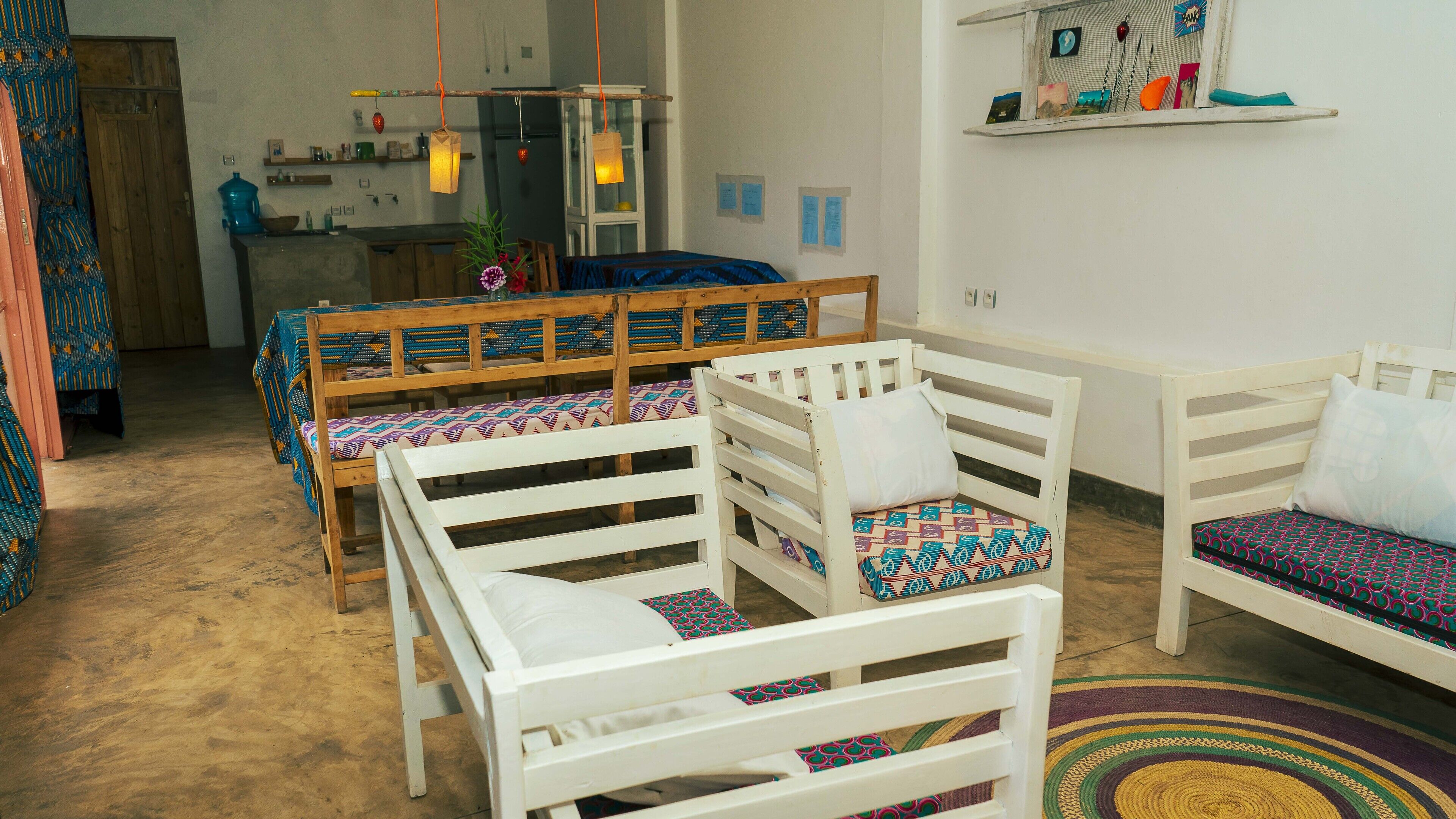 A cozy room with white furniture, a patterned rug, and a kitchen area in the background.