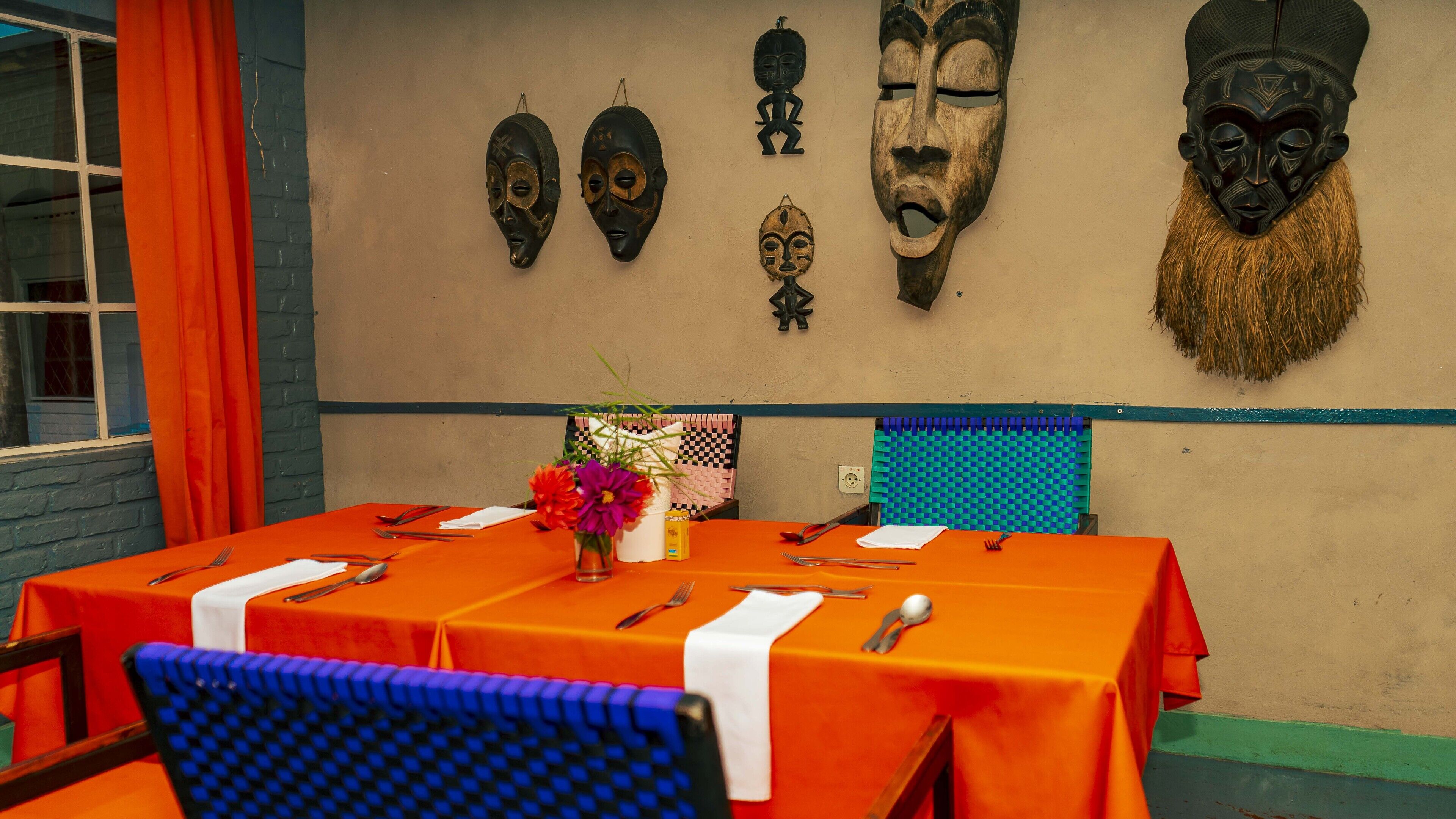 Un comedor con una mesa dispuesta para cuatro, con manteles anaranjados y sillas azules.