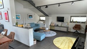 A modern living space with a blue sofa, a dining area, and a kitchen.