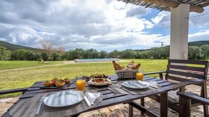 An outdoor dining setup with a table set for two, overlooking a grassy area and a swimming pool. - Burro Ville - Serene Houses w/ Pool by HostWise (Portimão)