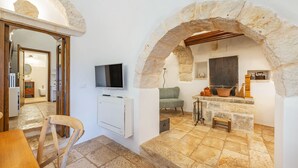 Una habitación acogedora con paredes de piedra, una silla de madera, un televisor y una chimenea de piedra.