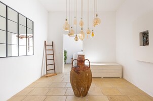 Una habitación amplia con un jarrón grande, una escalera de madera y un banco.