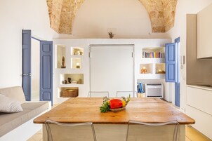 Una cocina moderna con una isla de madera, estanterías abiertas con adornos y vistas al área de estar con un sofá y cojines.