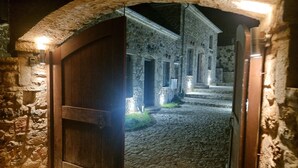 Un arco de entrada que da a un edificio de piedra con un camino adoquinado.