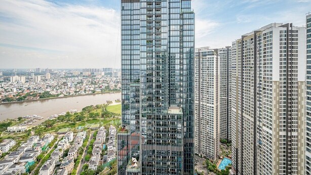 A high-rise building with a modern glass facade, surrounded by other residential buildings and a river in the background. - SaigonHomes in Vinhomes Central Park (Ho Chi Minh City)
