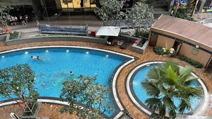 A large indoor swimming pool with a circular design, surrounded by lounge chairs and palm trees. - SaigonHomes in Vinhomes Central Park (Ho Chi Minh City)