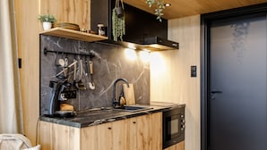 A compact kitchen with a wooden countertop, a black sink, and a built-in oven. - Description (Waarde)