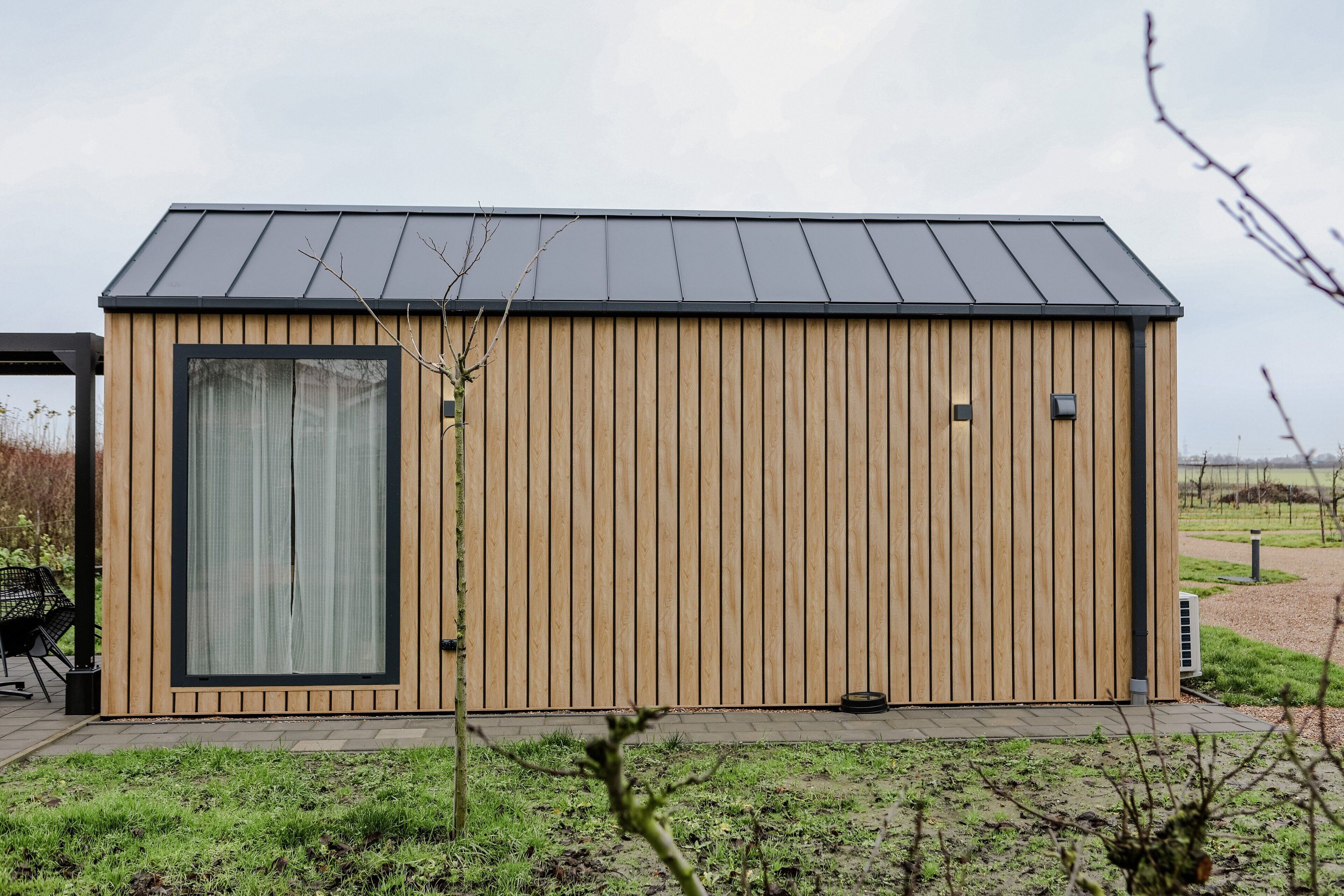 Un edificio moderno in legno con un'ampia finestra e un tetto in metallo.