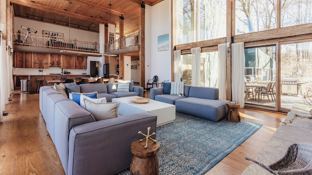 A spacious living area with a high ceiling, a large window, and a view of the outdoors.