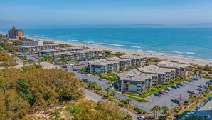 Un quartier résidentiel en bord de mer, avec des immeubles d’appartements modernes, une plage et un parking.