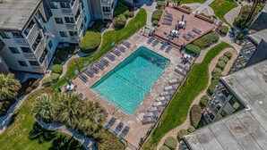 Vue aérienne d’un hôtel doté d’une piscine centrale, de chaises longues et d’un jardin aménagé.