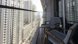 A balcony with a view of high-rise buildings, a small table, and two chairs. - Luxurious Waterfront 1BR with Sea Views (Dubai)