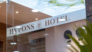Een hotelschild met de naam 'HYPONS HOTEL' en een decoratief glazen plafond.