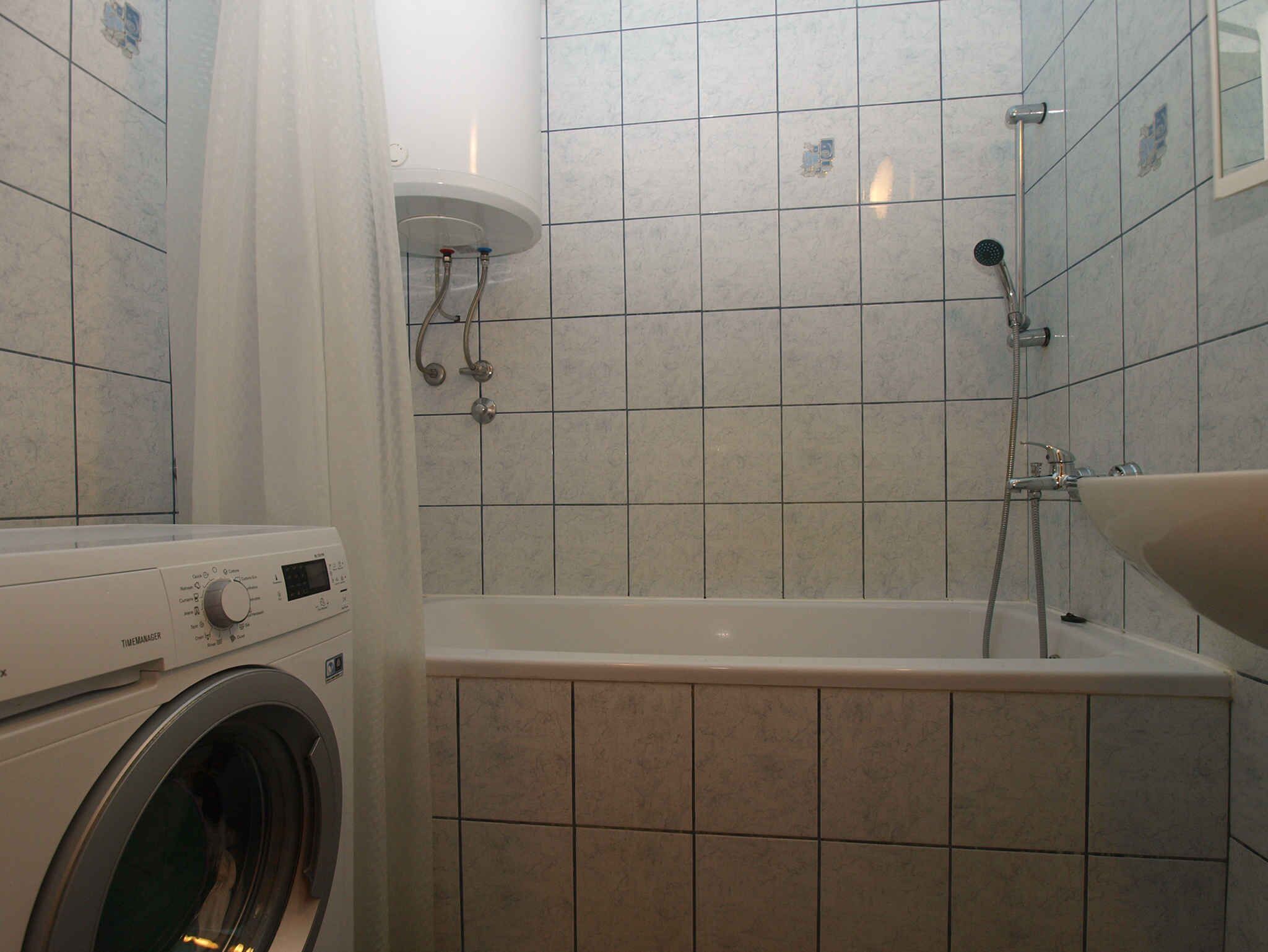 A bathroom with a washing machine, a bathtub, and a shower.