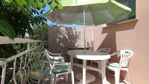 A patio with a table and four chairs, an umbrella, and a white fence. - Holiday apartment with air conditioning (Banjole)
