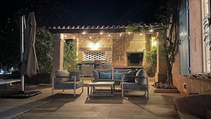 An outdoor patio area with stone walls, a grill, and a TV mounted on the wall.