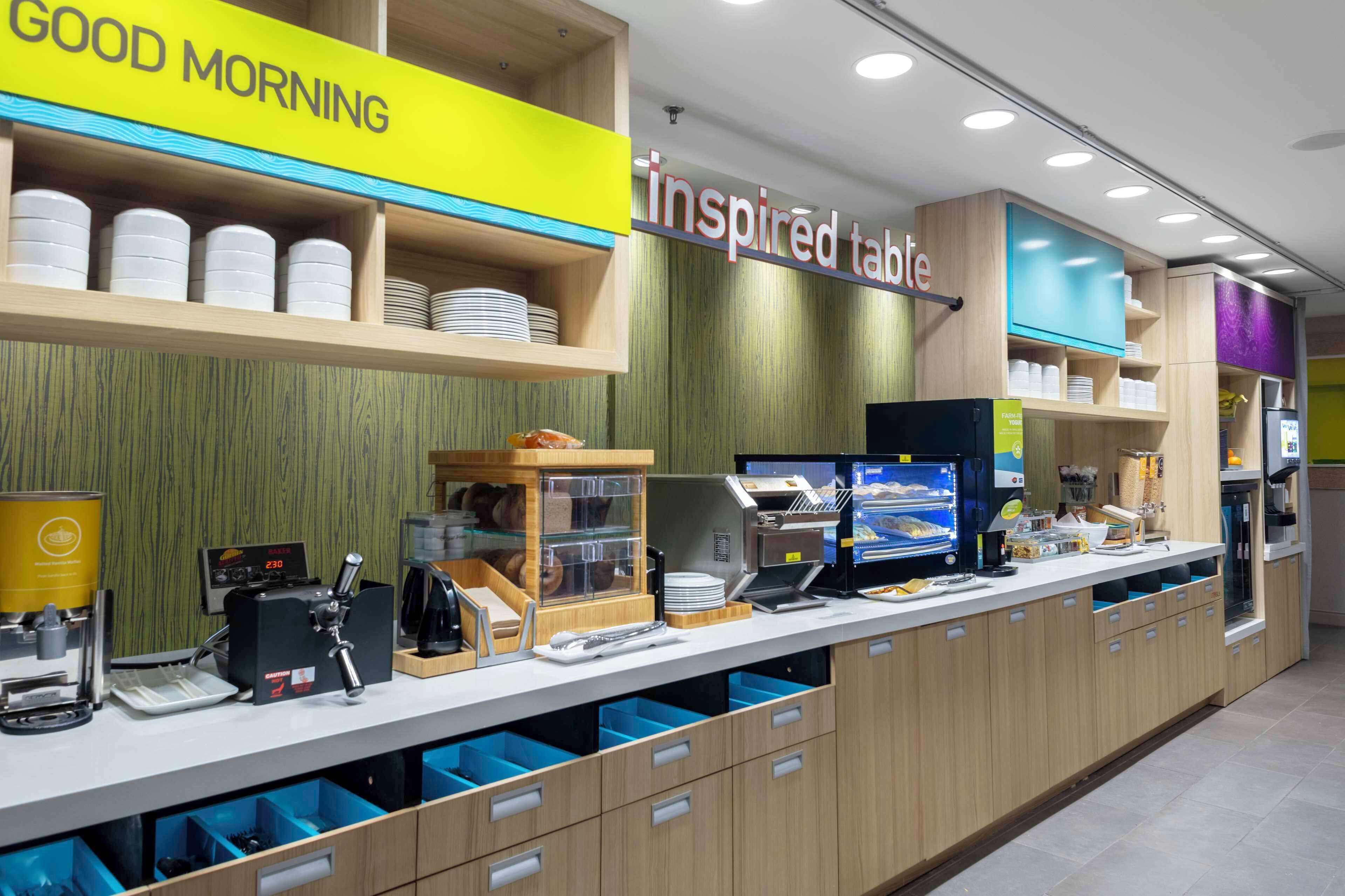 A breakfast bar with a 'Good Morning' sign, a digital menu board, and a coffee machine.