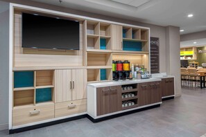 A modern kitchen with built-in cabinets, a central island, and a flat-screen TV. - Home2 Suites Lynchburg (Lynchburg)