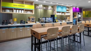 Een modern café met een ontbijtbalk, een zithoek en zelfbedieningskoffieautomaten.