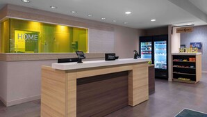 Een receptiebalie in een hotel met een modern design, een minibar en een automaat voor zelfbediening drankjes.