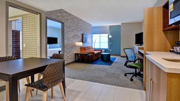Een hotelkamer met een eethoek, een woonkamer met een bank en televisie, en een kitchenette.