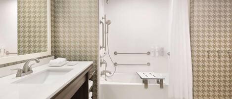 Un baño moderno con tocador doble lavamanos, ducha con barras de apoyo y bañera.