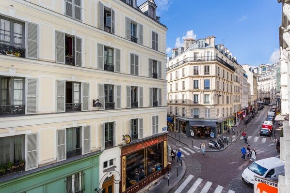 Vista de una calle en una ciudad europea, con edificios de varios pisos, un café y automóviles estacionados.
