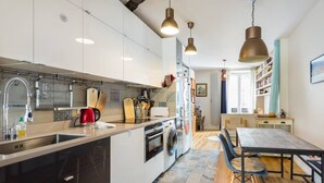 Eine moderne Küche mit weißen Schränken, einem eingebauten Backofen und einem Essbereich mit einem Holztisch und Stühlen.