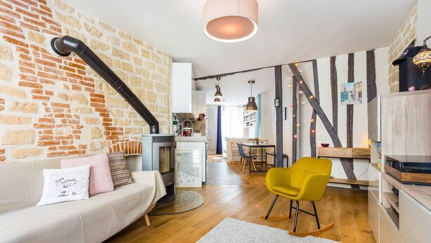 Ein modernes Wohnzimmer mit Backsteinwand, einer Couch, einem gelben Sessel und einem Kamin.